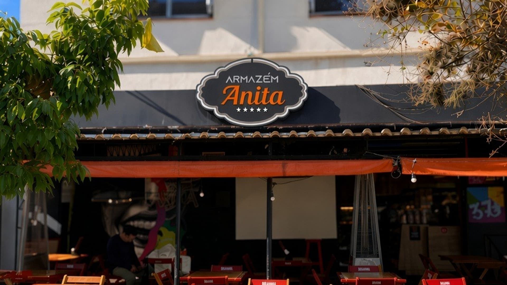 Fachada do Armazém Anita — mesas na calçada, toldo laranja e letreiro no Jardim Botânico